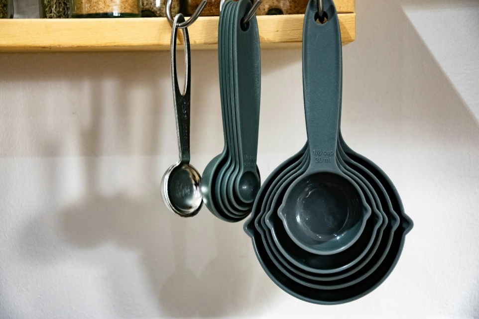 a set of measuring spoons hanging from a wooden rack